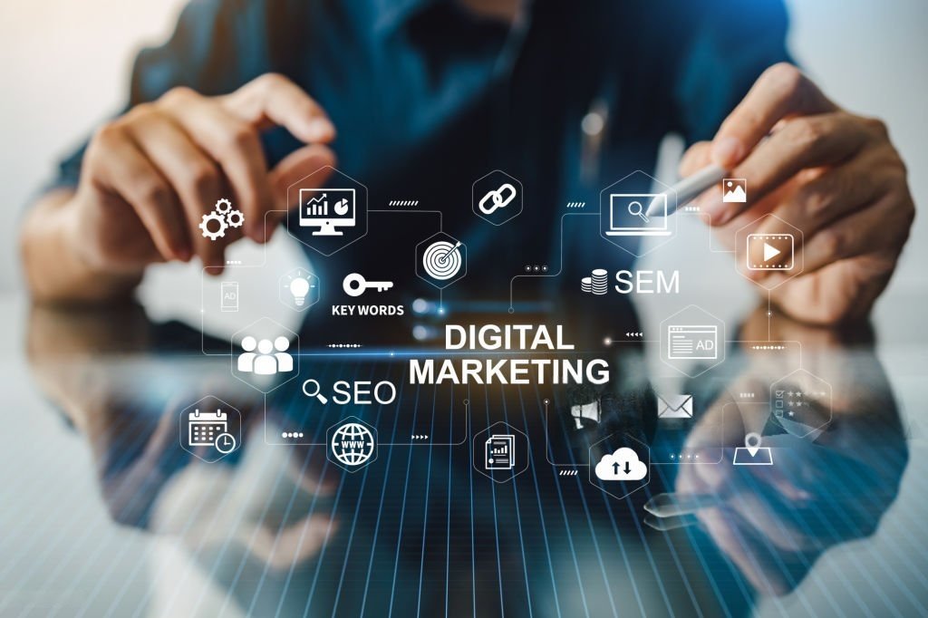 Digital marketing concept with SEO, SEM, keywords, analytics, and social media icons displayed on virtual screen, person using tablet and stylus in background.